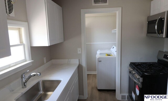 interior space featuring wood finished floors, a sink, stainless steel appliances, white cabinets, and visible vents