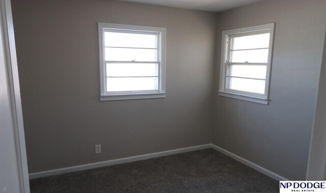 unfurnished room with dark carpet and baseboards
