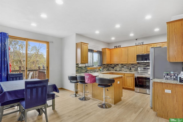kitchen featuring a peninsula, tasteful backsplash, appliances with stainless steel finishes, and plenty of natural light