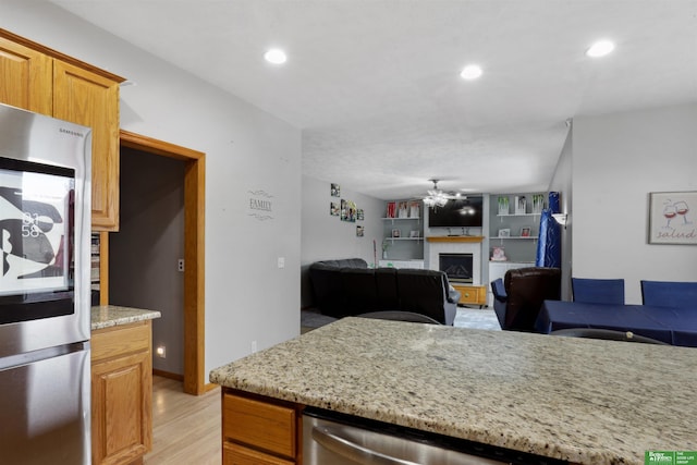 kitchen featuring light wood-style floors, ceiling fan, stainless steel appliances, a fireplace, and recessed lighting