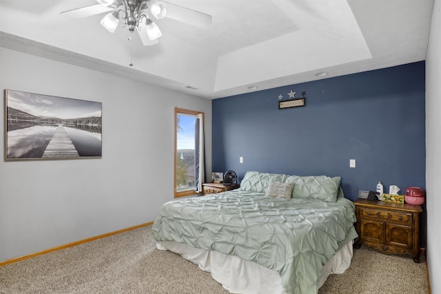 bedroom featuring baseboards, a ceiling fan, a tray ceiling, and carpet flooring