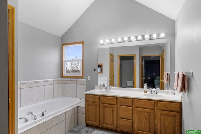 full bathroom with a bath, vaulted ceiling, and a sink
