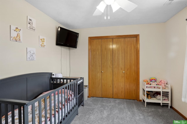 carpeted bedroom with ceiling fan, a crib, and a closet