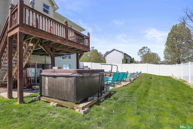 view of yard featuring a wooden deck, a hot tub, a fenced backyard, and stairs