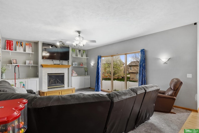 living area featuring a fireplace, wood finished floors, a ceiling fan, and baseboards