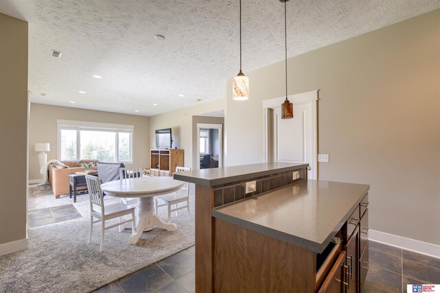 4510 W High Ridge Pl, Lincoln, NE 68522 - kitchen featuring stone tile floors, dark countertops, baseboards, and a center island