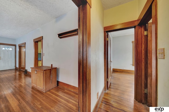 hall featuring hardwood / wood-style flooring, baseboards, and a textured ceiling