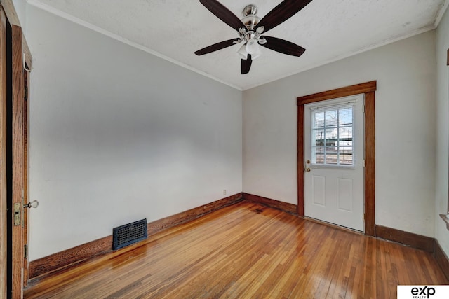 foyer entrance featuring ceiling fan, light wood finished floors, baseboards, ornamental molding, and visible vents