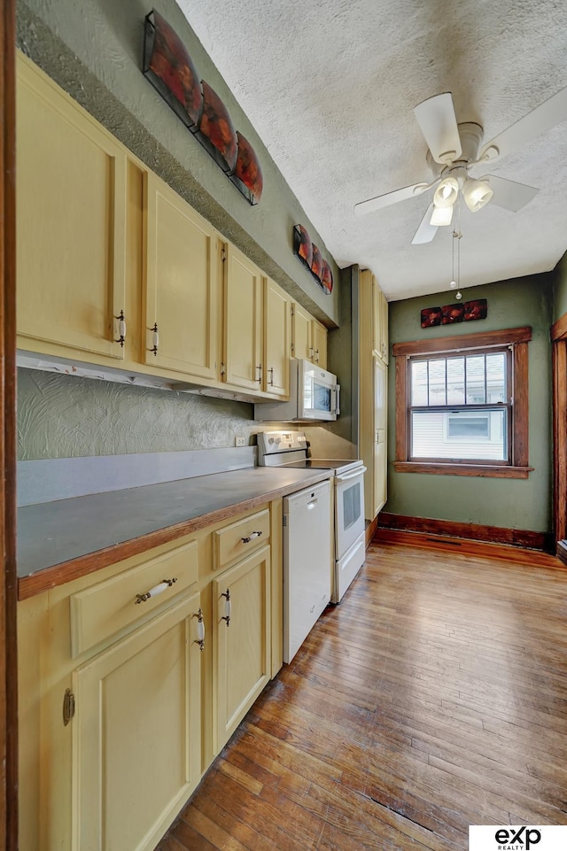 kitchen with baseboards, hardwood / wood-style flooring, white appliances, and a ceiling fan