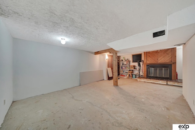 finished below grade area featuring a glass covered fireplace and a textured ceiling