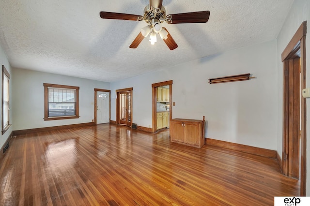 unfurnished living room with ceiling fan, baseboards, a textured ceiling, and visible vents