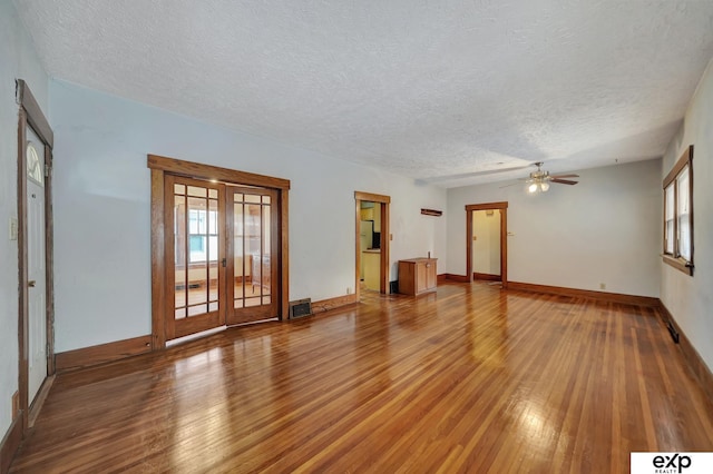 unfurnished living room featuring a healthy amount of sunlight, a textured ceiling, ceiling fan, and wood-type flooring