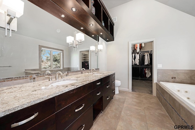 full bath with a sink, double vanity, an inviting chandelier, a jetted tub, and tile patterned flooring