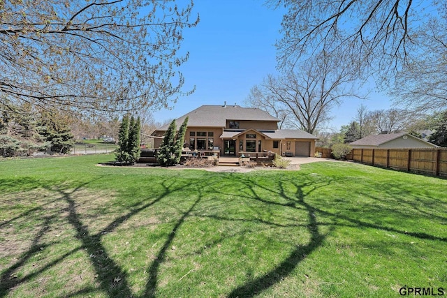 rear view of house with driveway, an attached garage, fence, a yard, and a wooden deck