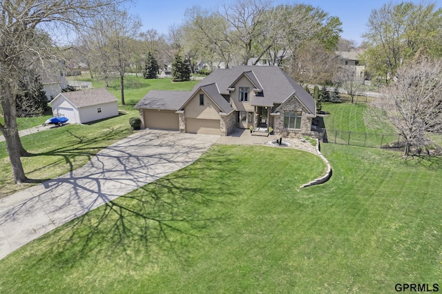 view of front facade with driveway, stone siding, fence, a front yard, and a garage