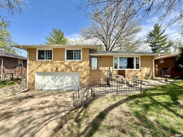 split level home with concrete driveway, brick siding, and a garage