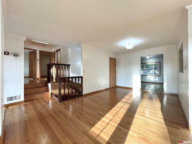empty room with baseboards, visible vents, hardwood / wood-style flooring, and ornamental molding