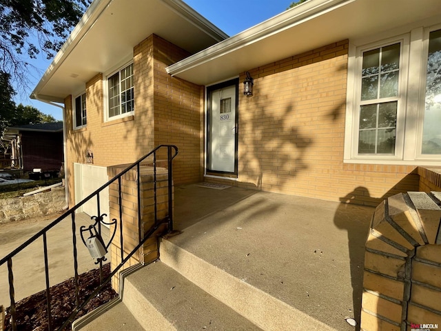 entrance to property with brick siding and a patio