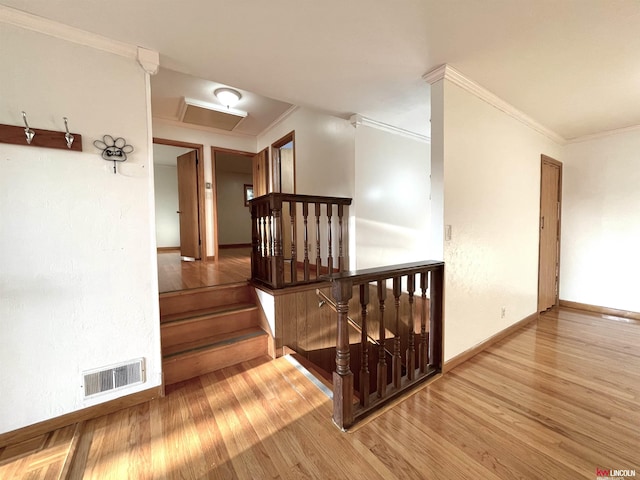 stairs featuring attic access, wood finished floors, visible vents, and ornamental molding