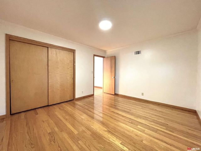 unfurnished bedroom featuring baseboards, visible vents, light wood finished floors, and a closet
