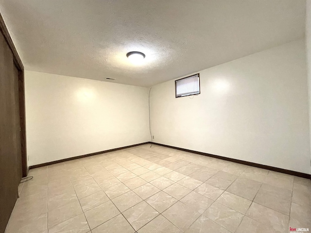unfurnished room with baseboards, light tile patterned flooring, and a textured ceiling