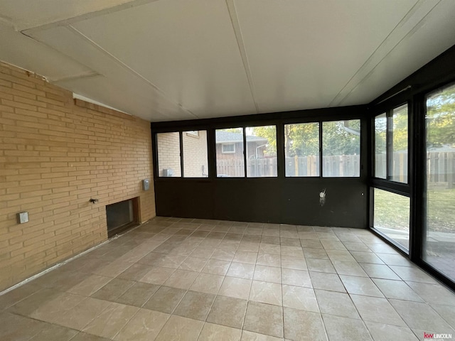 unfurnished sunroom featuring brick wall and tile patterned floors