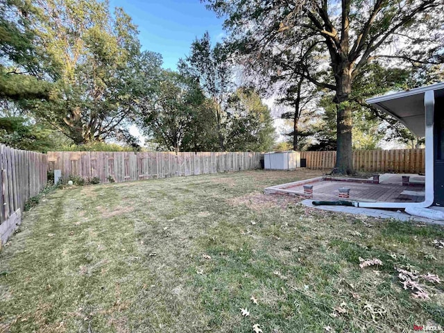 view of yard with a storage shed, a fenced backyard, an outdoor structure, and a deck