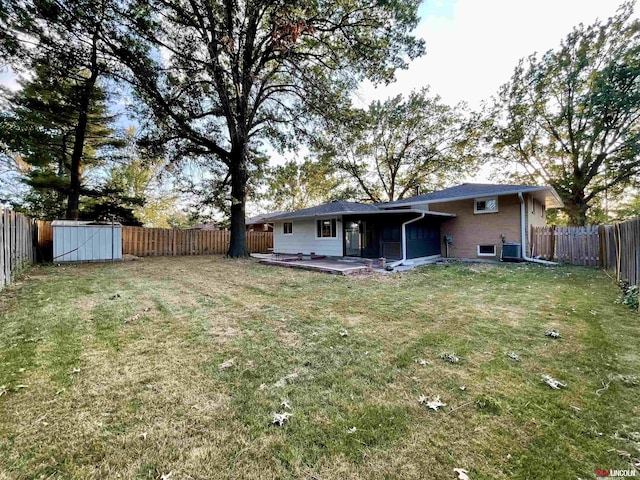 back of property with a deck, a fenced backyard, an outdoor structure, a yard, and a storage unit