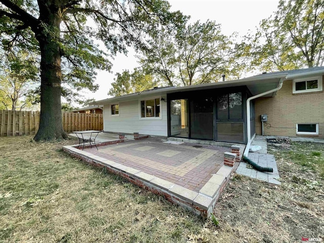rear view of house with a yard, a sunroom, a patio, and fence