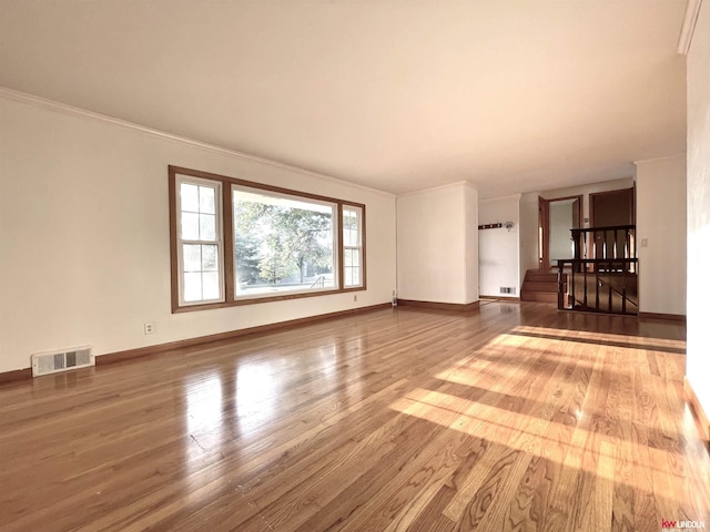 unfurnished living room featuring baseboards, wood finished floors, and visible vents