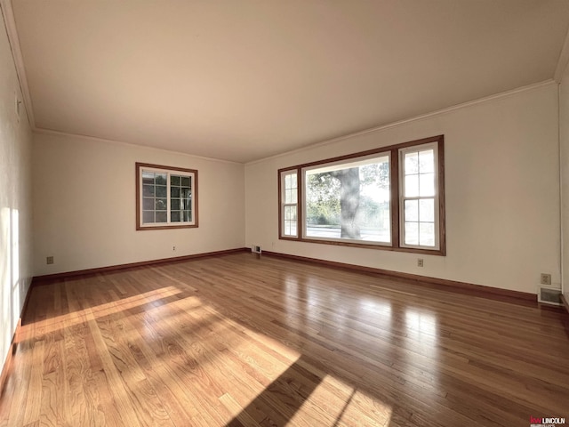 unfurnished room with baseboards, crown molding, wood finished floors, and visible vents