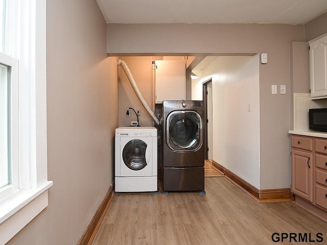 clothes washing area with light wood finished floors, washer and dryer, laundry area, and baseboards