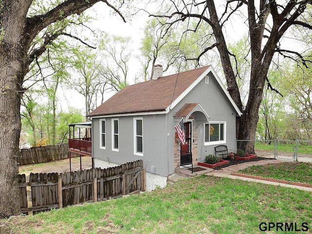 view of front of property with a chimney, a shingled roof, a front lawn, and a fenced backyard