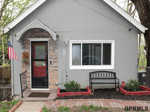 entrance to property featuring fence and stone siding