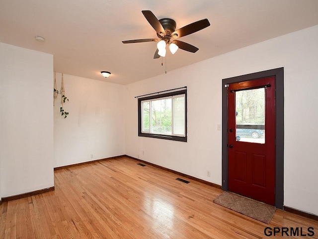 foyer entrance with visible vents, a ceiling fan, light wood-style flooring, and baseboards