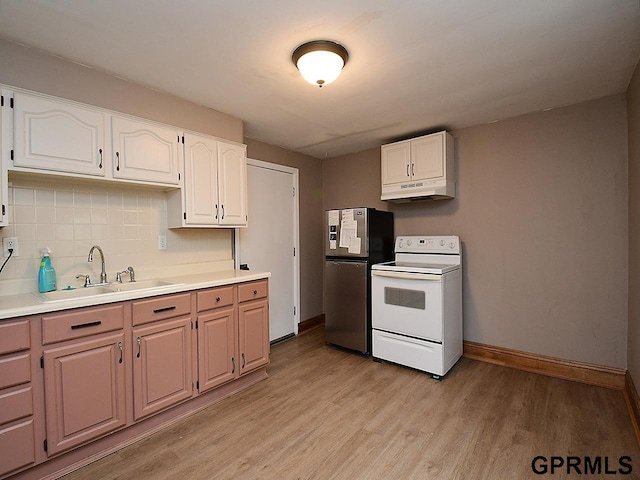 kitchen featuring tasteful backsplash, a sink, light wood-style floors, freestanding refrigerator, and electric range