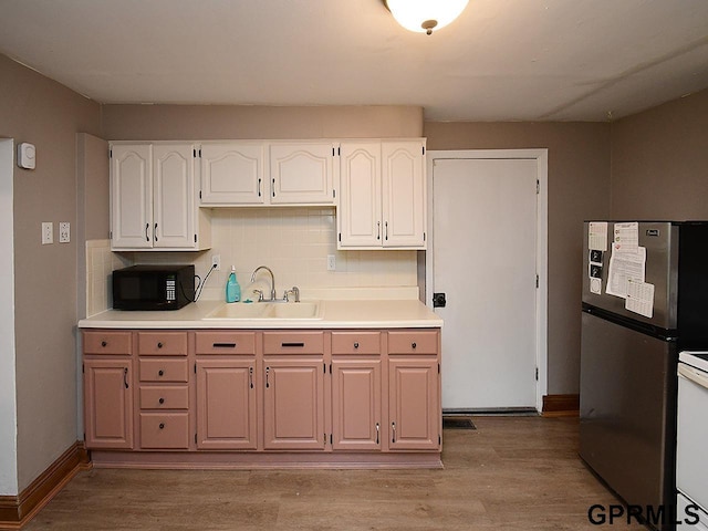 kitchen featuring decorative backsplash, light wood-style floors, a sink, white cabinetry, and black microwave
