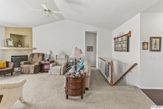 living room featuring a tiled fireplace, baseboards, a ceiling fan, and vaulted ceiling
