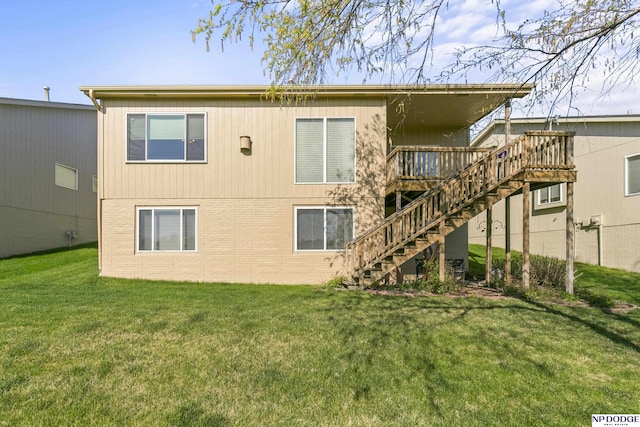 rear view of property with stairway, brick siding, fence, a wooden deck, and a lawn