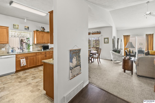 kitchen with white dishwasher, a sink, visible vents, a ceiling fan, and open floor plan