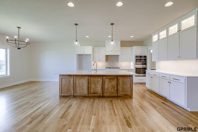 20806 Boulder St, Gretna, NE 68028 - kitchen with appliances with stainless steel finishes, backsplash, a sink, light wood-type flooring, and a notable chandelier