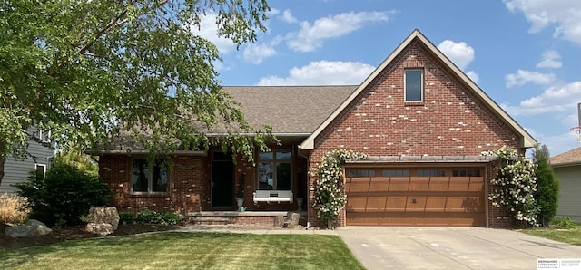 view of front of house with brick siding, roof with shingles, a front lawn, concrete driveway, and an attached garage