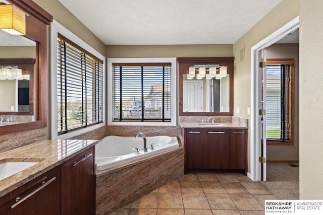 bathroom with a garden tub, two vanities, a sink, and tile patterned floors