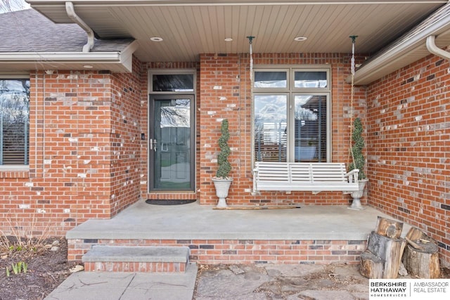 property entrance with covered porch and brick siding