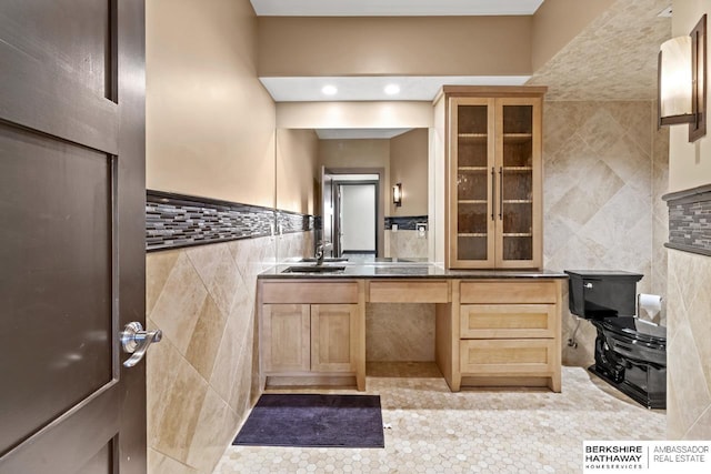 kitchen featuring glass insert cabinets, light brown cabinets, light tile patterned floors, tile walls, and a sink