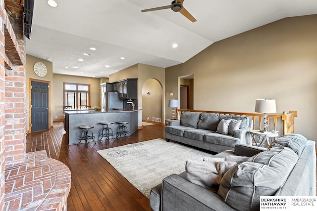 living area with recessed lighting, ceiling fan, vaulted ceiling, arched walkways, and dark wood finished floors