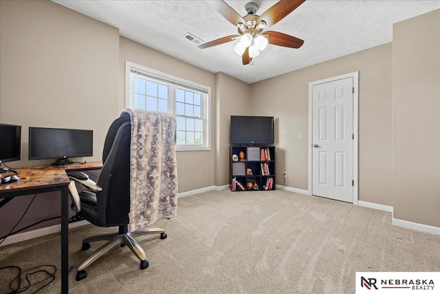 home office with a textured ceiling, ceiling fan, visible vents, baseboards, and carpet