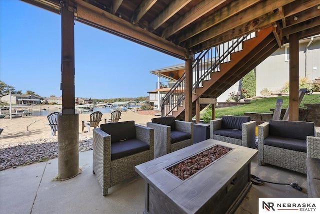 view of patio with stairway, a water view, and an outdoor living space with a fire pit