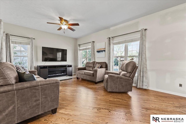living room featuring wood finished floors, ceiling fan, and baseboards