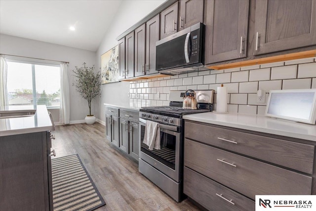 708 Sunset Blvd, Palmyra, NE 68418 - kitchen featuring stainless steel appliances, decorative backsplash, lofted ceiling, light countertops, and light wood-type flooring